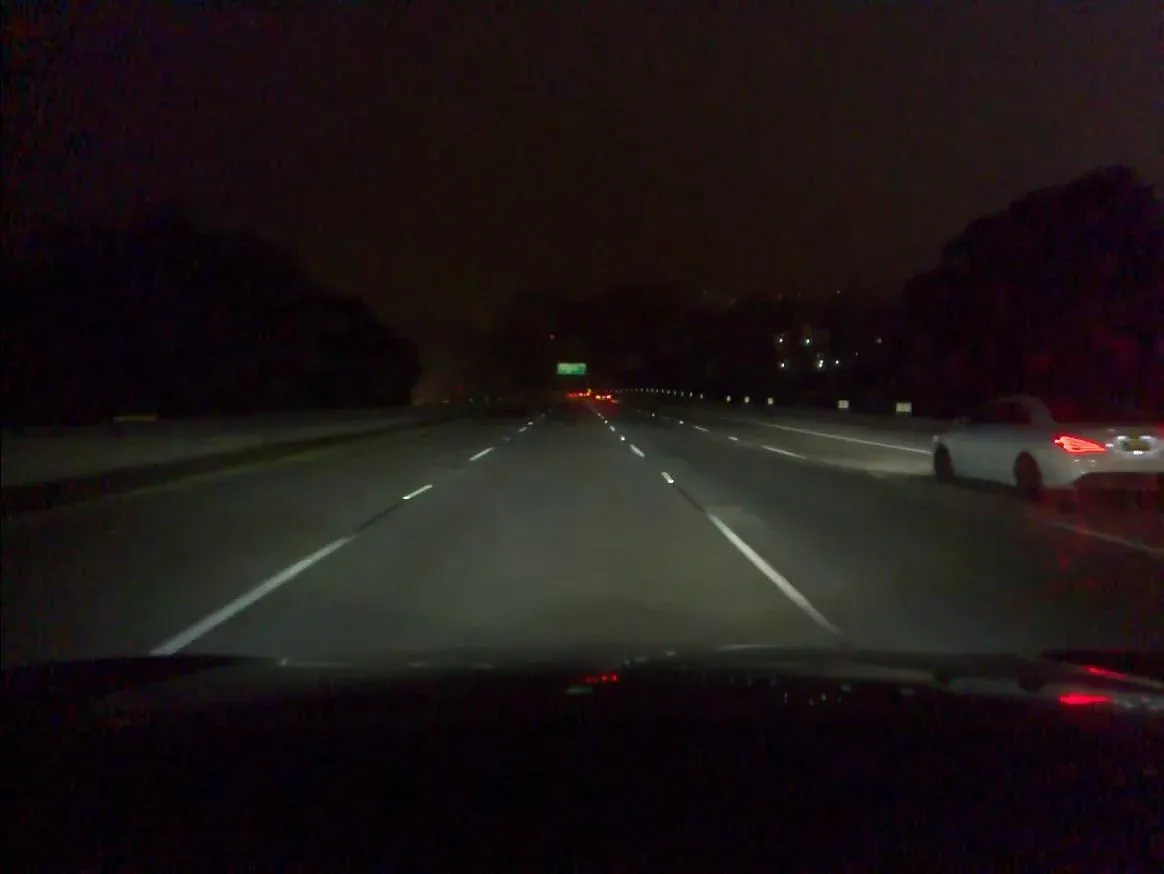 Nighttime highway frame with a white car on the right