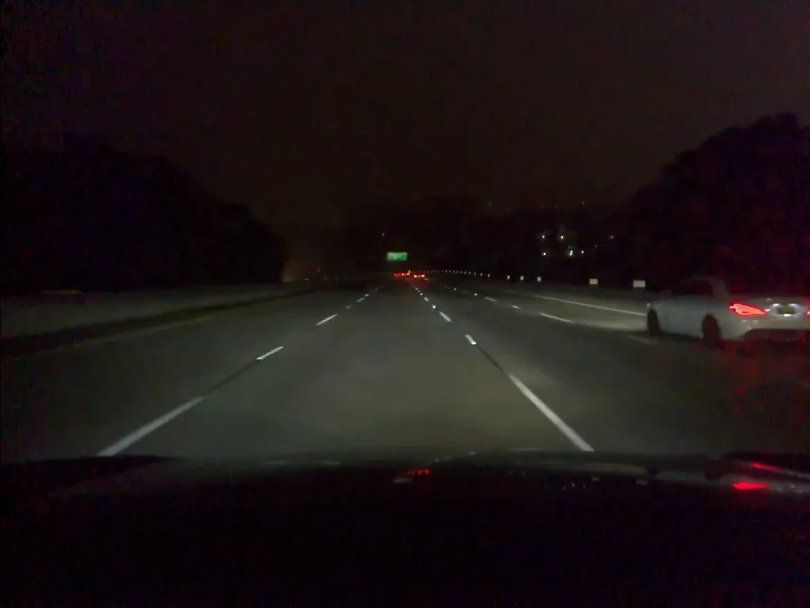 Nearly identical nighttime highway frame with a white car on the right